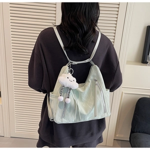 Detail view of a pale green soft leather backpack with side pockets and a cloud charm