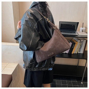 Detail of a vintage dark brown matte suede shoulder bag worn with a black leather jacket