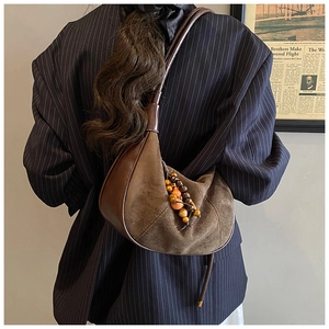 Detail of coffee suede shoulder bag featuring bohemian wooden bead fringe charms