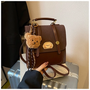 Details des braunen Wildleder-Rucksacks mit Hunde-Aufnäher und Plüschbär-Anhänger