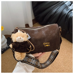 Détail du sac polochon marron mat avec bandoulière à motifs et breloque ourson
