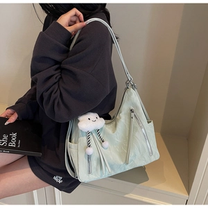 Detail of light green large capacity tote bag with silver zippers and plush cloud charm