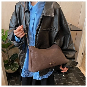 Detail view of a retro matte dark brown crossbody hobo bag worn with a stylish leather jacket