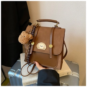 Nahaufnahme des braunen Vintage-Rucksacks mit Welpen-Patch und Teddybär-Anhänger