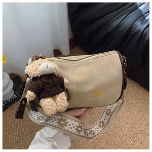 Détail du sac polochon beige avec bandoulière ethnique et breloque ours en peluche