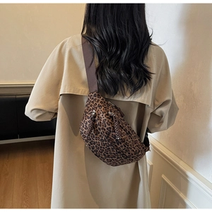 Detailed view of leopard print crossbody bag worn by model in a neutral indoor setting