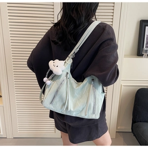 Detail view of mint green pleated crossbody bag with cloud plush pendant on a model