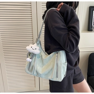 Detail of mint green tote bag featuring a plush cloud charm and metal zipper accents