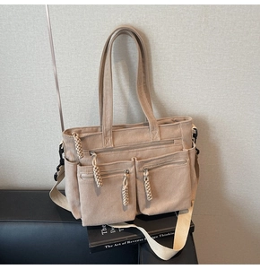 Detail of beige corduroy tote bag showing multiple front pockets and woven zipper pulls