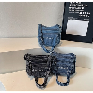 Detail view of denim crossbody bags in light blue, medium blue, and charcoal grey wash