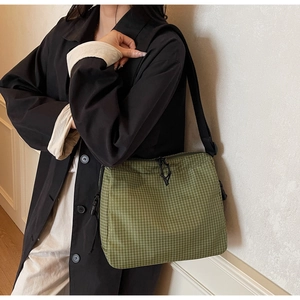 Close-up of green checkered canvas tote bag with adjustable black shoulder strap