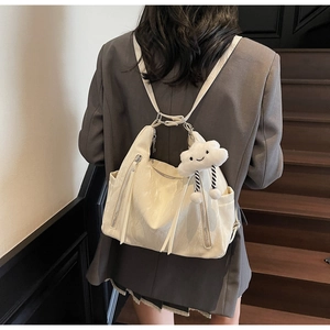 Detail of a creamy white pleated leather hobo bag featuring a cute cloud plush pendant
