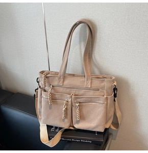 Detail of khaki corduroy tote bag showing multiple zipper pockets and striped fabric texture