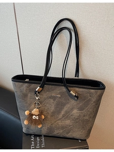 Deep grey vintage tote bag with marble texture and plush monster charm in a studio shot