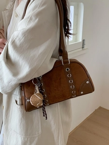 Vintage brown suede Boston bag with metal eyelets and cat charm shown on shoulder