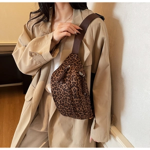 Detail of leopard print chest bag showing canvas texture and woven zipper puller on strap