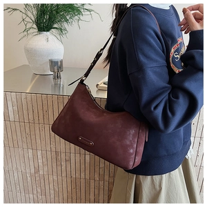 Detail view of burgundy matte leather crescent bag with adjustable strap on model