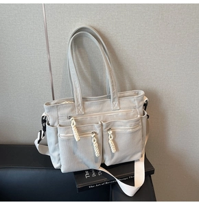 Detail of grey corduroy tote bag featuring three front zipper pockets and woven rope pulls
