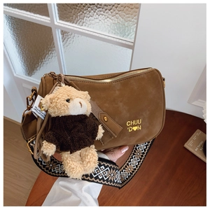 Détail du sac oreiller marron en daim avec bandoulière géométrique et breloque ours