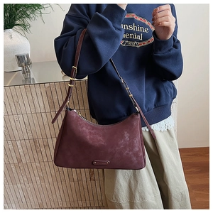 Detail view of vintage burgundy leather shoulder bag with gold logo on dark blue sweater