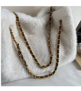 Detail of soft white plush bag with elegant gold metal and brown leather chain strap