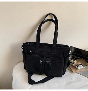 Close-up of black corduroy tote bag with multiple zip pockets and adjustable strap