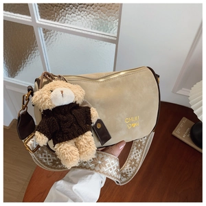 Détail du sac oreiller en daim beige avec breloque ours en peluche et sangle brodée