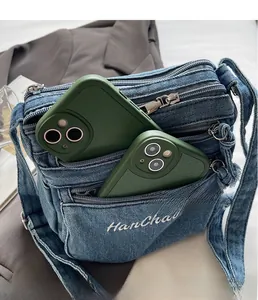 Detail view of denim shoulder bag interior with multi-pocket storage and dual mobile phones