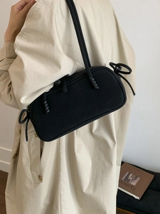 Sac bandoulière minimaliste noir mat pour femme avec un trench-coat beige