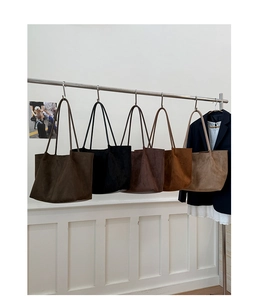 Detailed display of suede tote bags in five earthy tones hanging on a minimalist metal rack