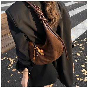 Detail of brown suede crescent bag with knotted strap and colorful beads on street