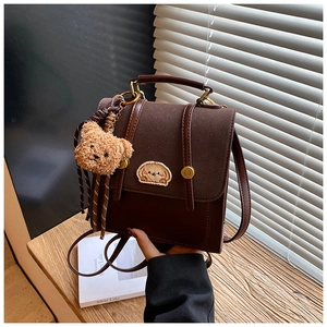 Detail eines braunen Vintage-Rucksacks mit Welpen-Stickerei und Plüschbär-Anhänger