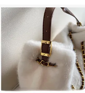 Detail of white faux fur bag with brown leather strap and gold metal buckle hardware