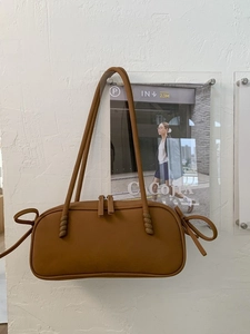 Sac à bandoulière marron en similicuir mat avec nœuds et fermeture éclair double sur mur