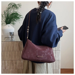 Close-up of wine red frosted hobo bag with gold logo plaque and adjustable strap detail