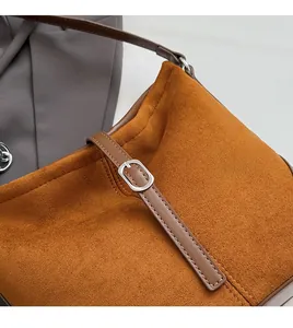 Détail de la texture suédée caramel avec sangle en cuir marron et boucle en métal argenté