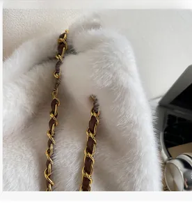 Close-up of white fluffy plush tote bag featuring luxury gold chain woven strap
