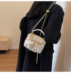 Detail of tweed crossbody bag with sequins, metal chain, and white plush charm on a model