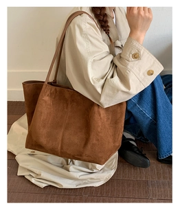 Close-up of warm brown suede tote bag with decorative vertical stitching and dual handles