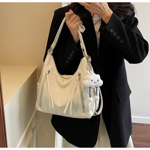 Detail of white glossy tote bag with silver zippers and a cute cloud plush charm