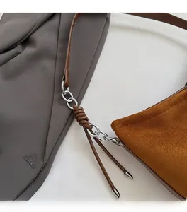 Gros plan d'un sac seau en daim marron avec chaîne en métal argenté et bandoulière tressée