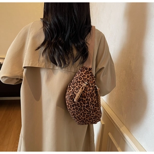 Detail of leopard print crossbody bag with woven rope zippers and wide fabric strap