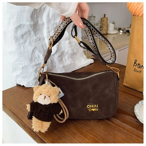 Détail du sac oreiller en daim avec bandoulière bohème et breloque ours en peluche