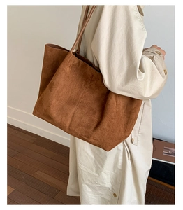 Detail view of large caramel suede tote bag worn on shoulder showing texture and capacity