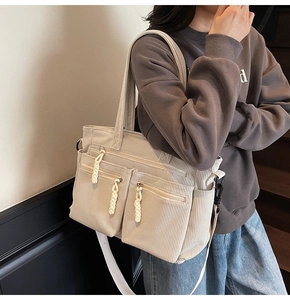 Detailed close-up of beige corduroy tote bag featuring three front zipper pockets and rope pulls