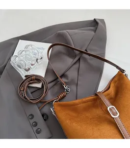 Détail du sac seau en daim fauve montrant les bords en cuir et la boucle en métal argenté