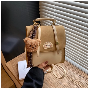 Nahaufnahme eines braunen Mini-Rucksacks mit Tierstickerei und Plüschbär-Anhänger