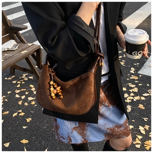 Brown suede shoulder bag detail with wooden bead tassels and bohemian knot shoulder strap