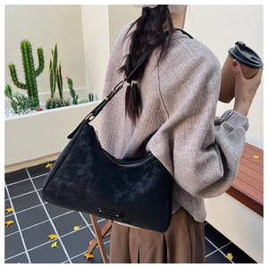 Macro detail of black matte textured crossbody bag with gold buckle on shoulder strap