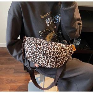 Detailed view of leopard print crossbody bag with adjustable brown strap and orange label
